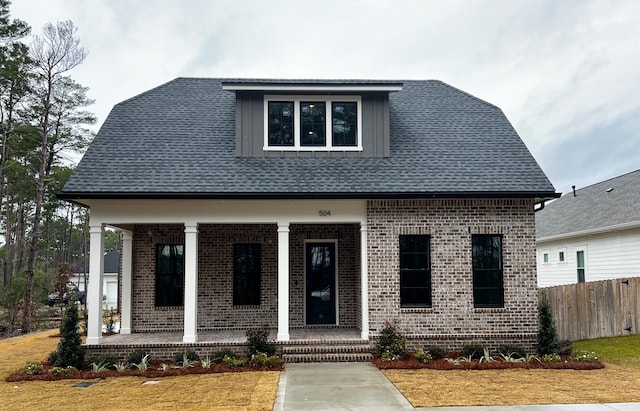 view of front of property featuring covered porch, roof with shingles, fence, and brick siding