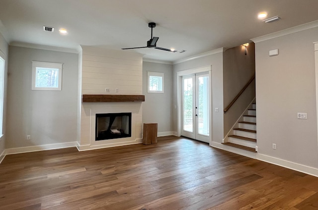 unfurnished living room featuring hardwood / wood-style floors, ceiling fan, a large fireplace, french doors, and ornamental molding