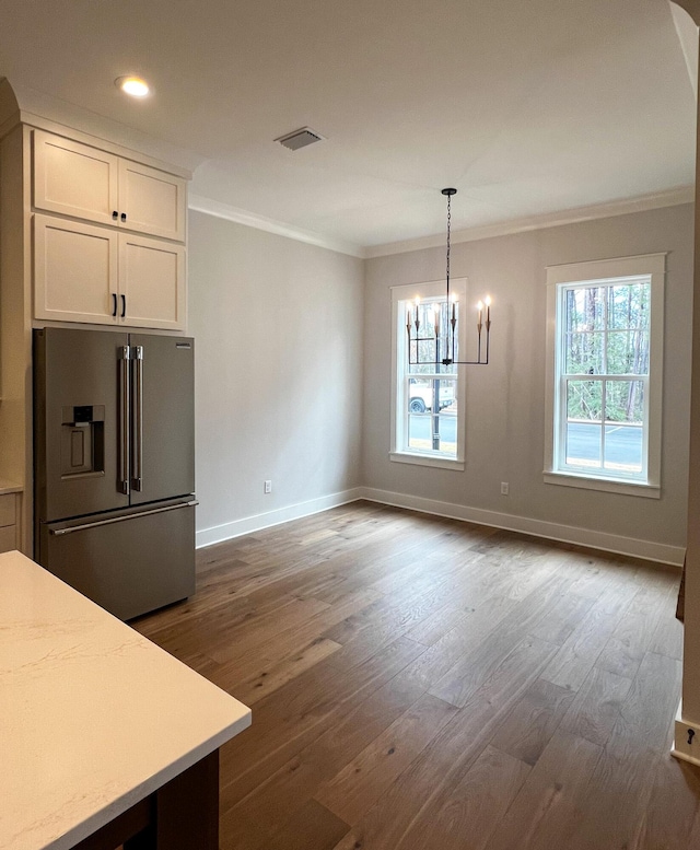 unfurnished dining area featuring crown molding, dark hardwood / wood-style floors, and a notable chandelier