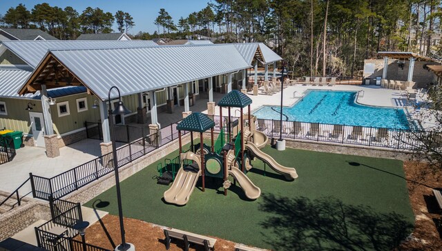 community playground featuring a patio area, a community pool, and fence