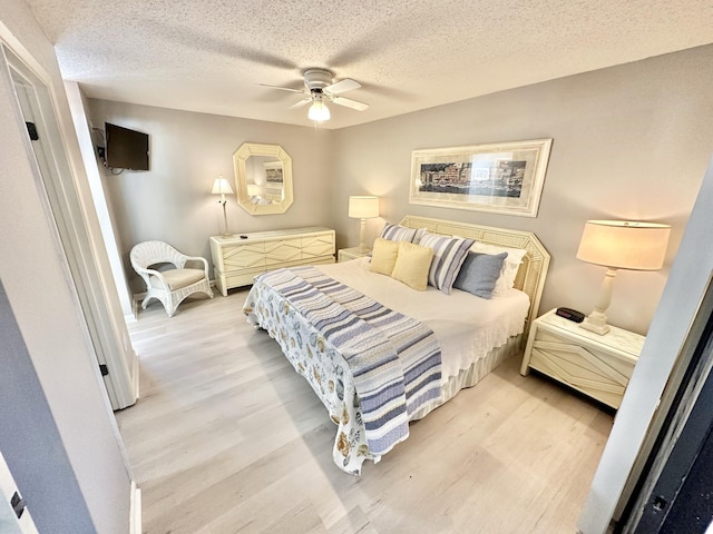 bedroom featuring ceiling fan, a textured ceiling, and light wood-type flooring