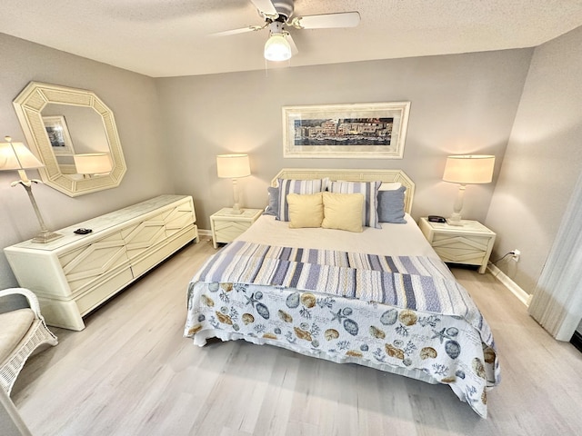 bedroom with ceiling fan, light hardwood / wood-style floors, and a textured ceiling