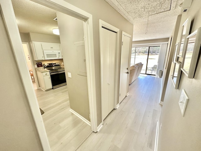 hall with a textured ceiling and light hardwood / wood-style flooring