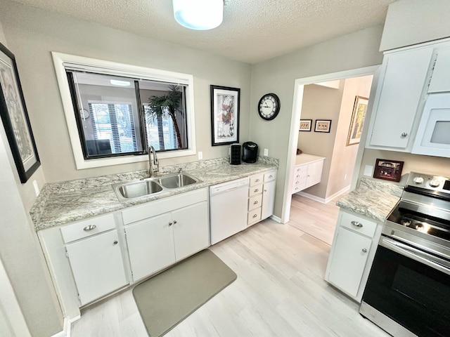 kitchen with white appliances, light wood-type flooring, a textured ceiling, white cabinets, and sink