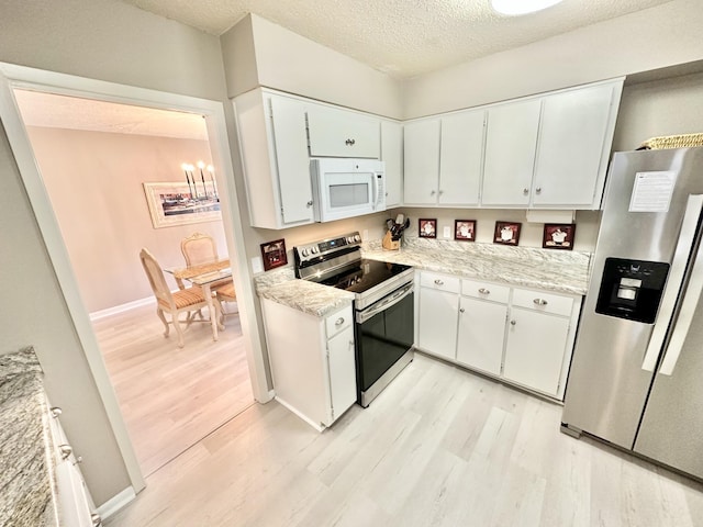 kitchen featuring a textured ceiling, white cabinets, stainless steel appliances, a notable chandelier, and light hardwood / wood-style flooring