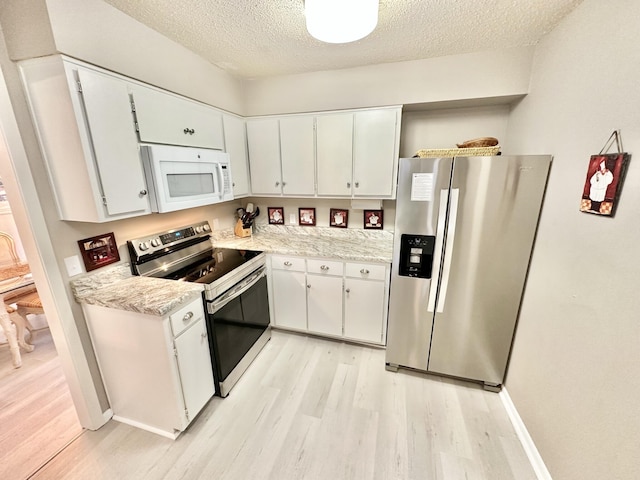 kitchen featuring a textured ceiling, stainless steel appliances, light hardwood / wood-style floors, and white cabinets