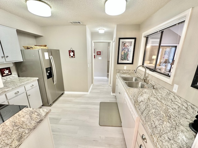 kitchen with a textured ceiling, dishwasher, white cabinets, and sink