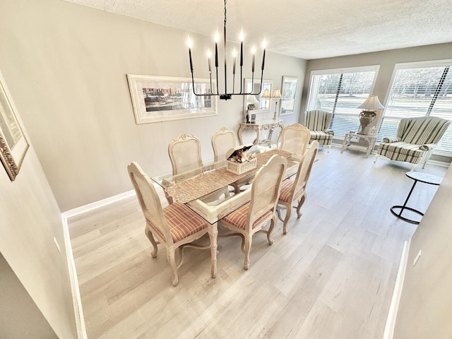 dining room with light hardwood / wood-style floors, a textured ceiling, and a notable chandelier