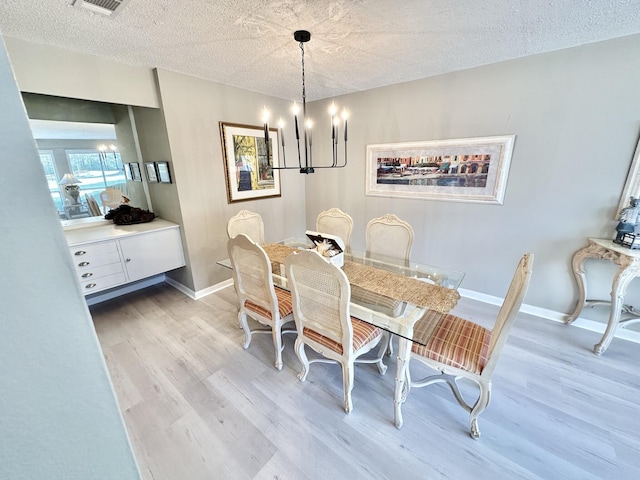 dining area with a chandelier, wood-type flooring, and a textured ceiling