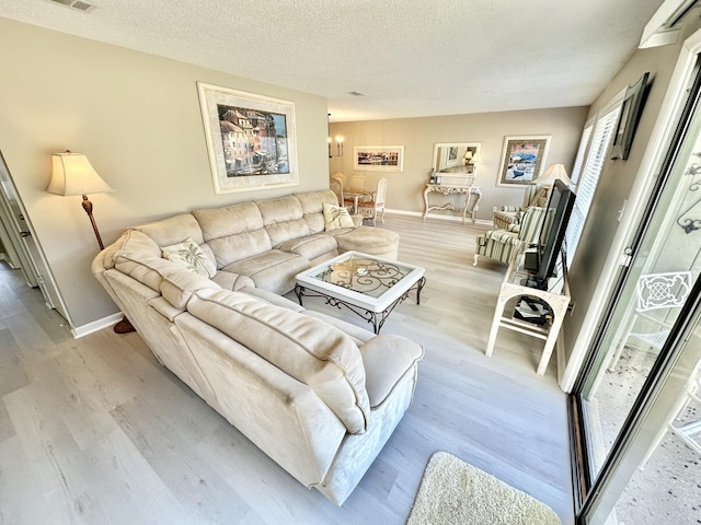 living room with a textured ceiling, light hardwood / wood-style flooring, and an inviting chandelier