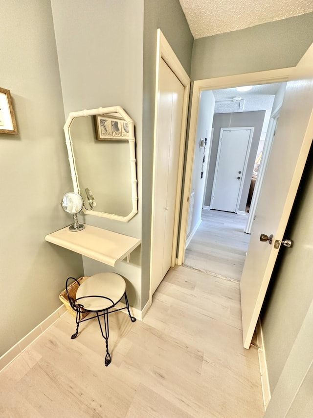 hall with light hardwood / wood-style floors and a textured ceiling