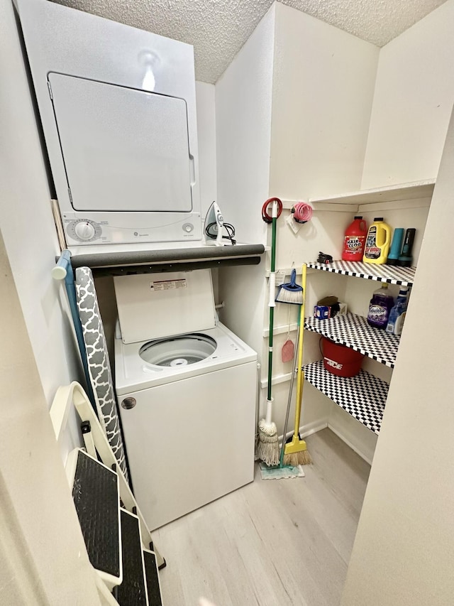 washroom with stacked washer and clothes dryer, a textured ceiling, and light hardwood / wood-style floors