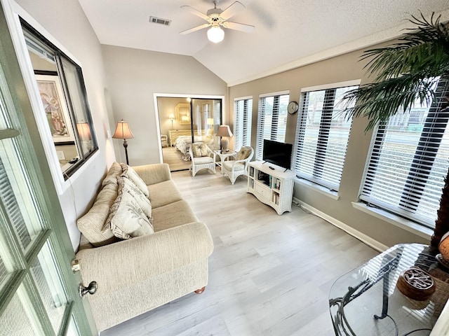 living room with light hardwood / wood-style floors, ceiling fan, and vaulted ceiling