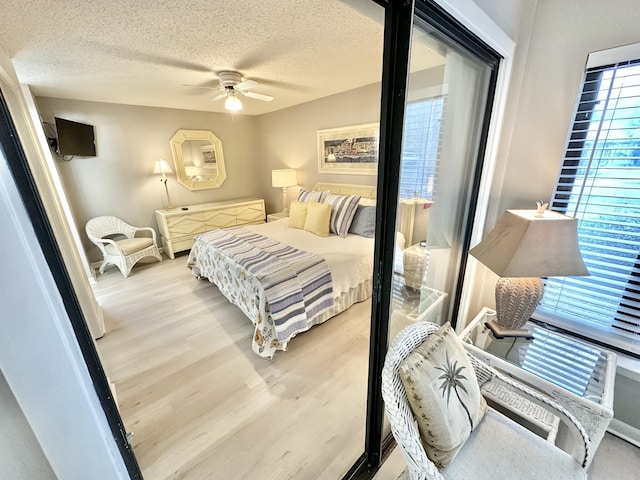 bedroom with ceiling fan, a textured ceiling, and light hardwood / wood-style floors