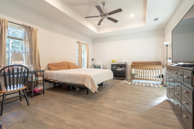 bedroom featuring a tray ceiling, ceiling fan, and hardwood / wood-style flooring