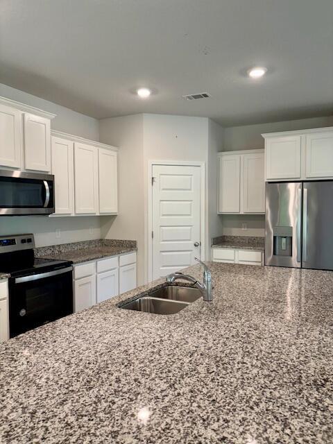 8177 Majestic Cypress Dr, Milton, FL 32583 - kitchen featuring a sink, appliances with stainless steel finishes, dark stone countertops, visible vents, and white cabinets
