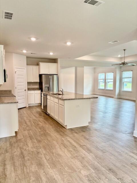 8177 Majestic Cypress Dr, Milton, FL 32583 - kitchen with open floor plan, stainless steel appliances, visible vents, light wood-style floors, and ceiling fan