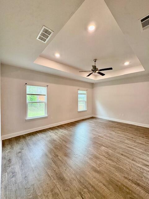8177 Majestic Cypress Dr, Milton, FL 32583 - unfurnished room featuring baseboards, visible vents, wood finished floors, and a raised ceiling