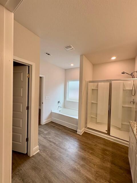 8177 Majestic Cypress Dr, Milton, FL 32583 - full bath featuring baseboards, a shower stall, a garden tub, visible vents, and wood finished floors