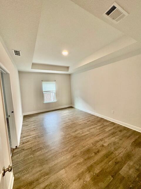 8177 Majestic Cypress Dr, Milton, FL 32583 - unfurnished room with a tray ceiling, baseboards, visible vents, and dark wood-style flooring