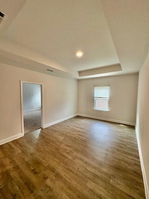 8177 Majestic Cypress Dr, Milton, FL 32583 - empty room featuring dark wood-style flooring, a tray ceiling, and baseboards