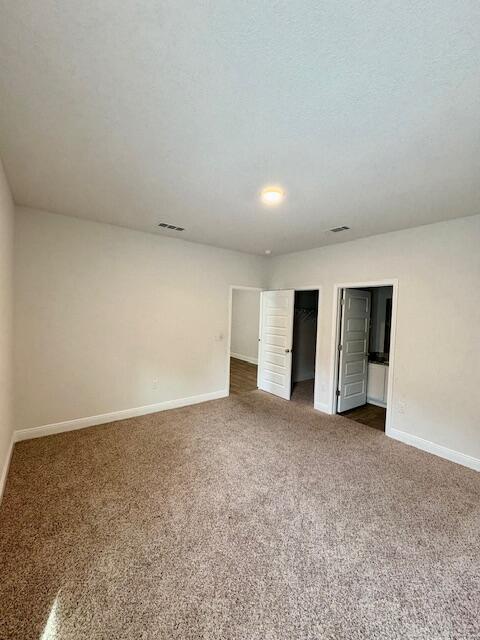 8177 Majestic Cypress Dr, Milton, FL 32583 - interior space featuring baseboards, visible vents, dark carpet, and a textured ceiling