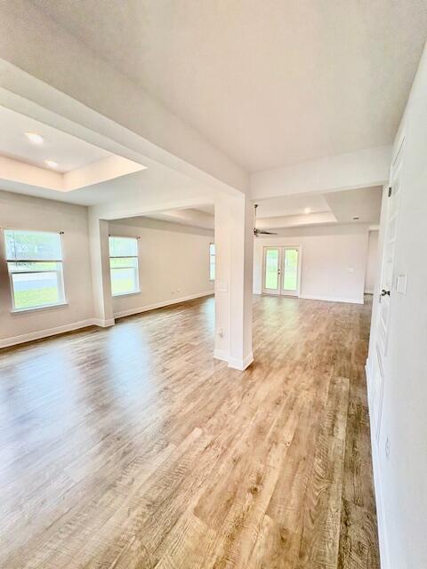 8177 Majestic Cypress Dr, Milton, FL 32583 - unfurnished room with a tray ceiling, baseboards, ceiling fan, and light wood-type flooring
