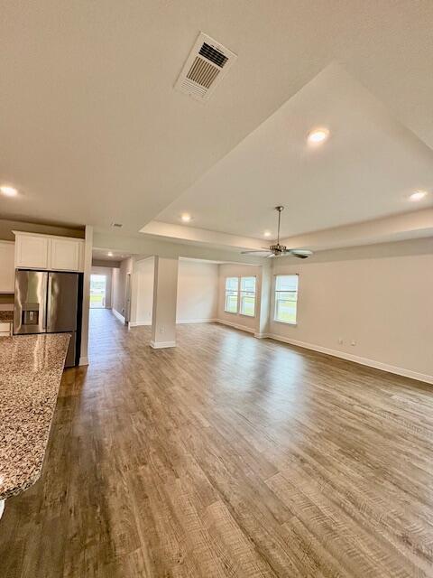 8177 Majestic Cypress Dr, Milton, FL 32583 - unfurnished living room with a tray ceiling, visible vents, dark wood-type flooring, and a ceiling fan
