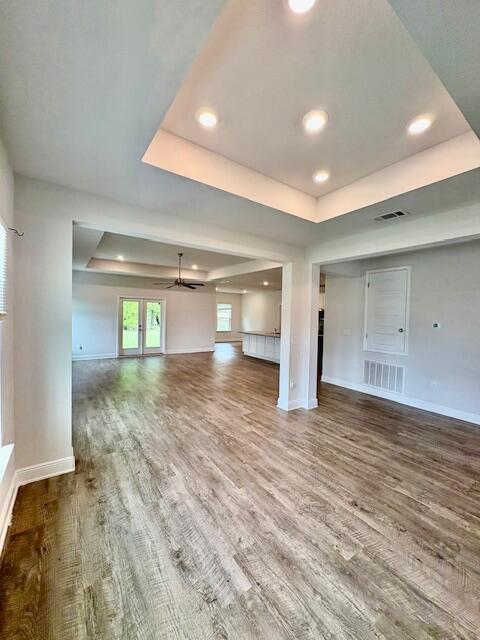 8177 Majestic Cypress Dr, Milton, FL 32583 - unfurnished living room featuring a tray ceiling, baseboards, visible vents, and wood finished floors