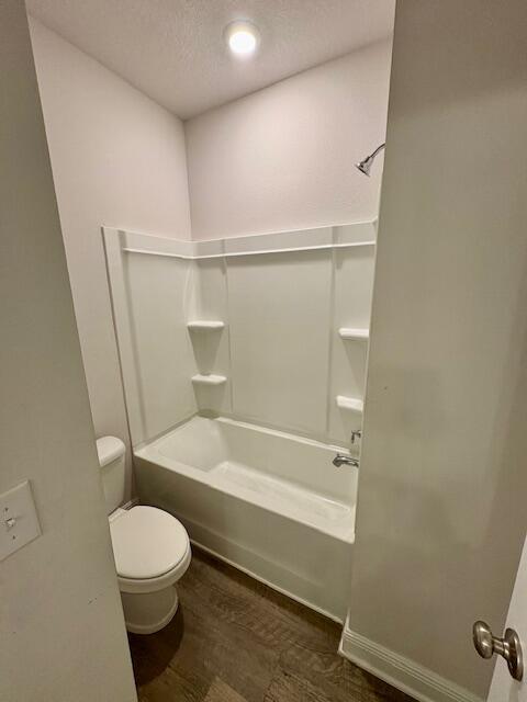 8177 Majestic Cypress Dr, Milton, FL 32583 - bathroom with  shower combination, a textured ceiling, toilet, and wood finished floors