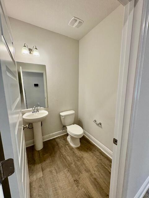 8177 Majestic Cypress Dr, Milton, FL 32583 - bathroom featuring visible vents, baseboards, wood finished floors, toilet, and a sink