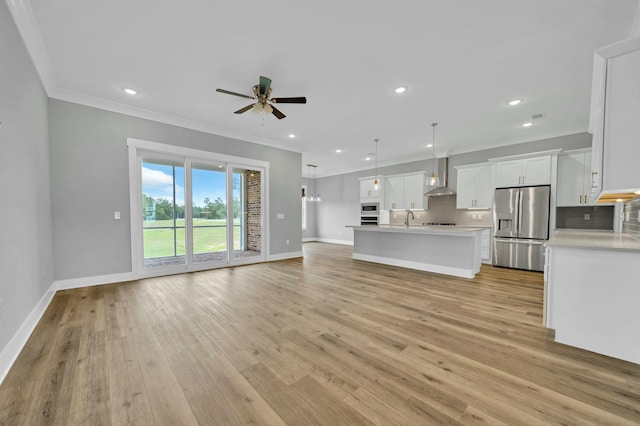 unfurnished living room featuring ceiling fan, sink, ornamental molding, and light wood-type flooring