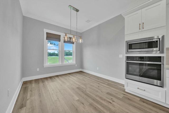 kitchen with appliances with stainless steel finishes, pendant lighting, light hardwood / wood-style floors, and white cabinetry