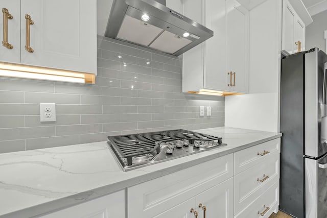 kitchen with light stone counters, white cabinetry, appliances with stainless steel finishes, and ventilation hood