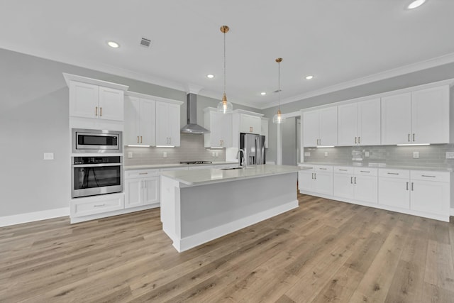 kitchen with decorative light fixtures, wall chimney range hood, white cabinets, and stainless steel appliances