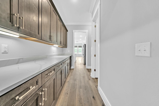 hall with ornamental molding and light hardwood / wood-style floors