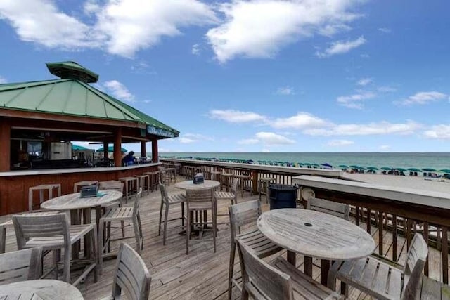 wooden deck with a water view, a gazebo, an outdoor bar, and a beach view