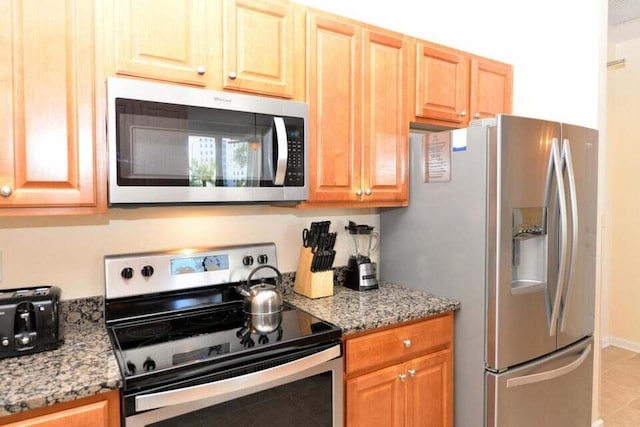 kitchen featuring appliances with stainless steel finishes, light tile patterned flooring, and light stone counters