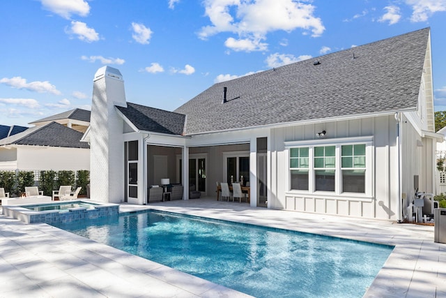 rear view of house featuring a pool with hot tub and a patio