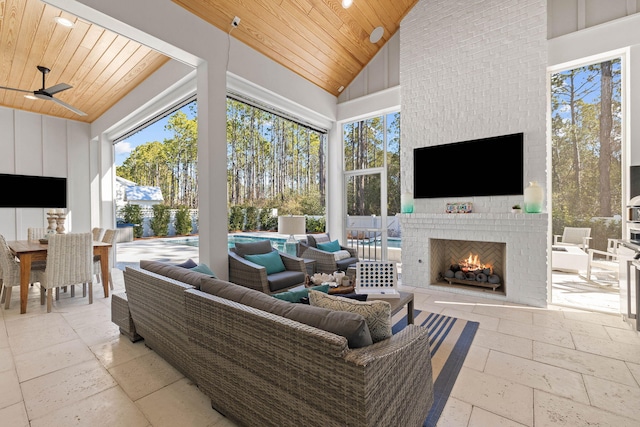 living room featuring high vaulted ceiling, ceiling fan, wood ceiling, and an outdoor brick fireplace