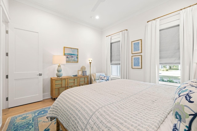 bedroom with ceiling fan, crown molding, and light hardwood / wood-style floors