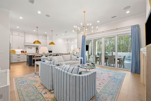 living room featuring light hardwood / wood-style floors, crown molding, and a chandelier