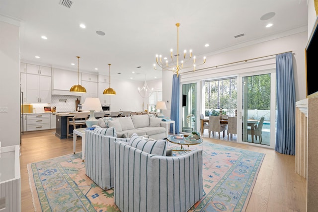 living room with light hardwood / wood-style flooring, ornamental molding, and a notable chandelier