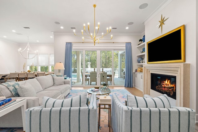 living room featuring built in features, a chandelier, ornamental molding, and light hardwood / wood-style flooring