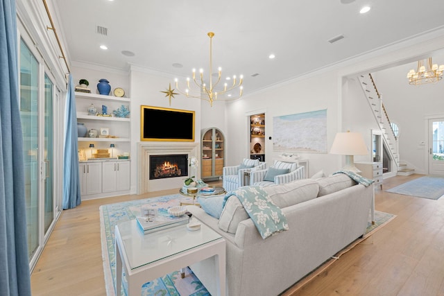 living room with light hardwood / wood-style flooring, built in features, a chandelier, and ornamental molding