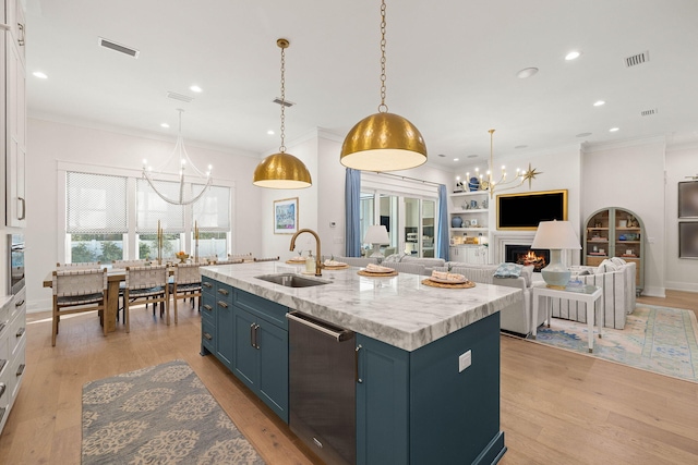 kitchen featuring pendant lighting, a center island with sink, sink, blue cabinetry, and white cabinets