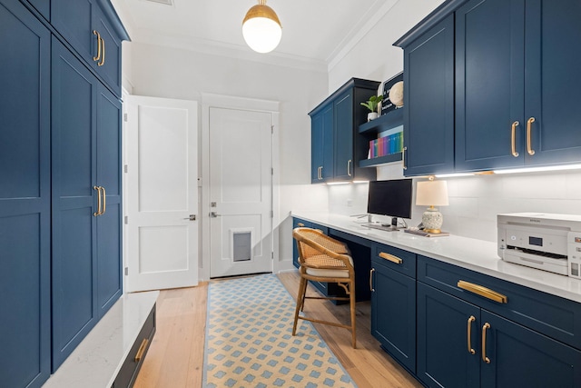 home office featuring built in desk, light wood-type flooring, and crown molding