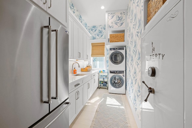 laundry area featuring stacked washer / dryer, sink, and light tile patterned flooring