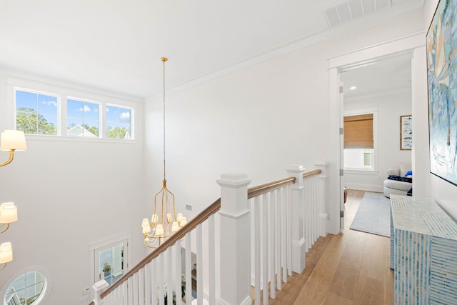 hall featuring crown molding, a chandelier, and light wood-type flooring