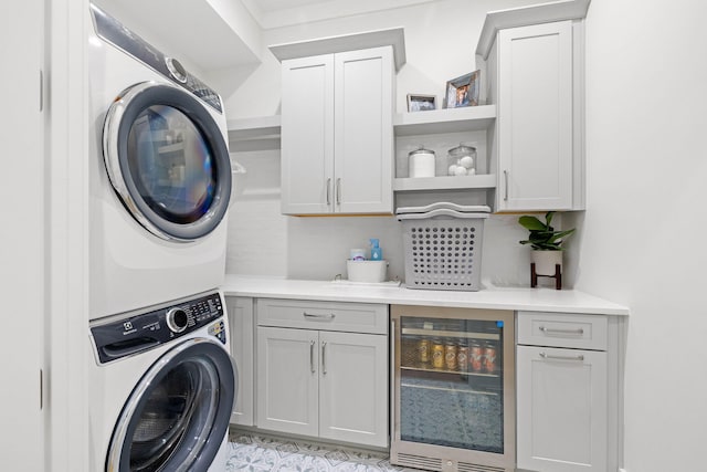 clothes washing area with stacked washer and dryer, cabinets, and wine cooler